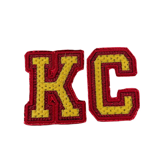 KC iron-on patch in Kansas City Chiefs colors with bold yellow "KC" letters outlined in red.