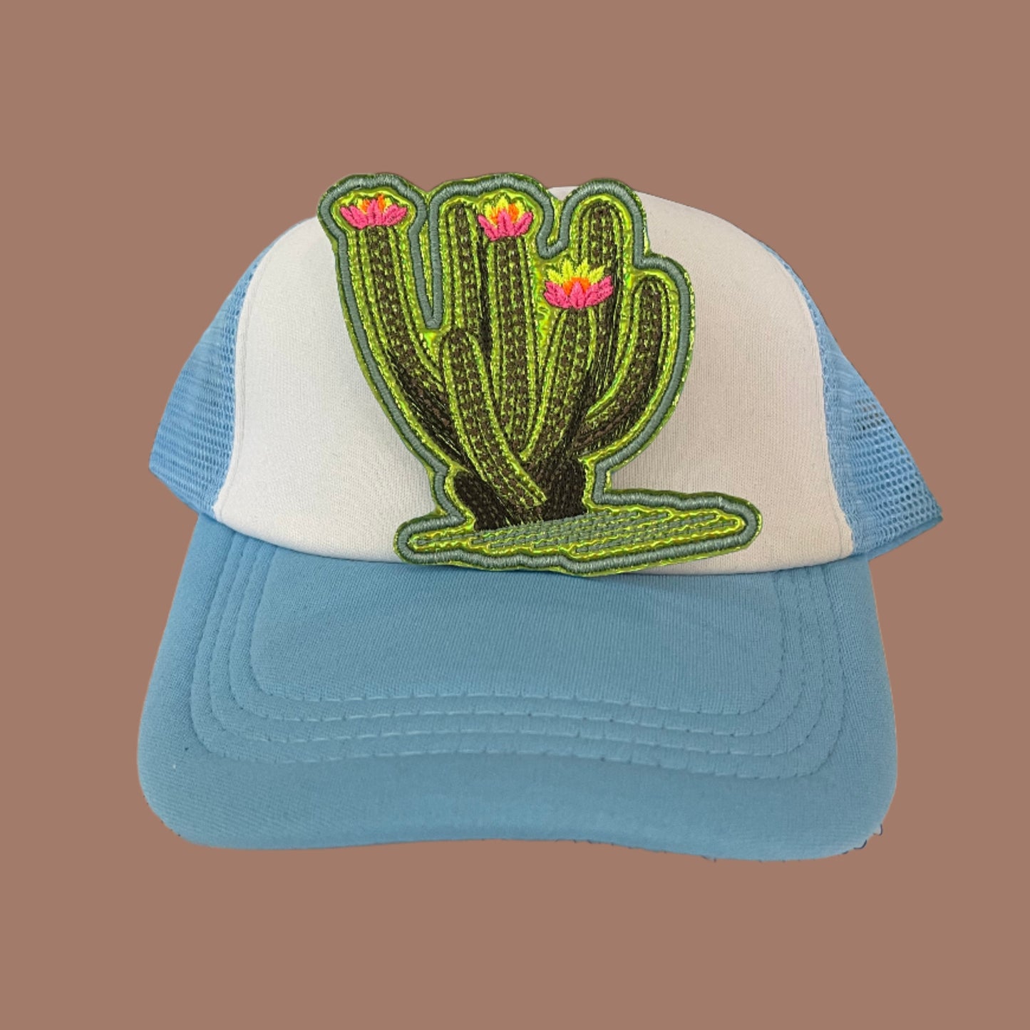 Iron-on patch featuring a large leggy cactus with neon yellow, neon orange, and neon pink flowers, green metallic vinyl showing through stitching gaps, and an aqua outline.
