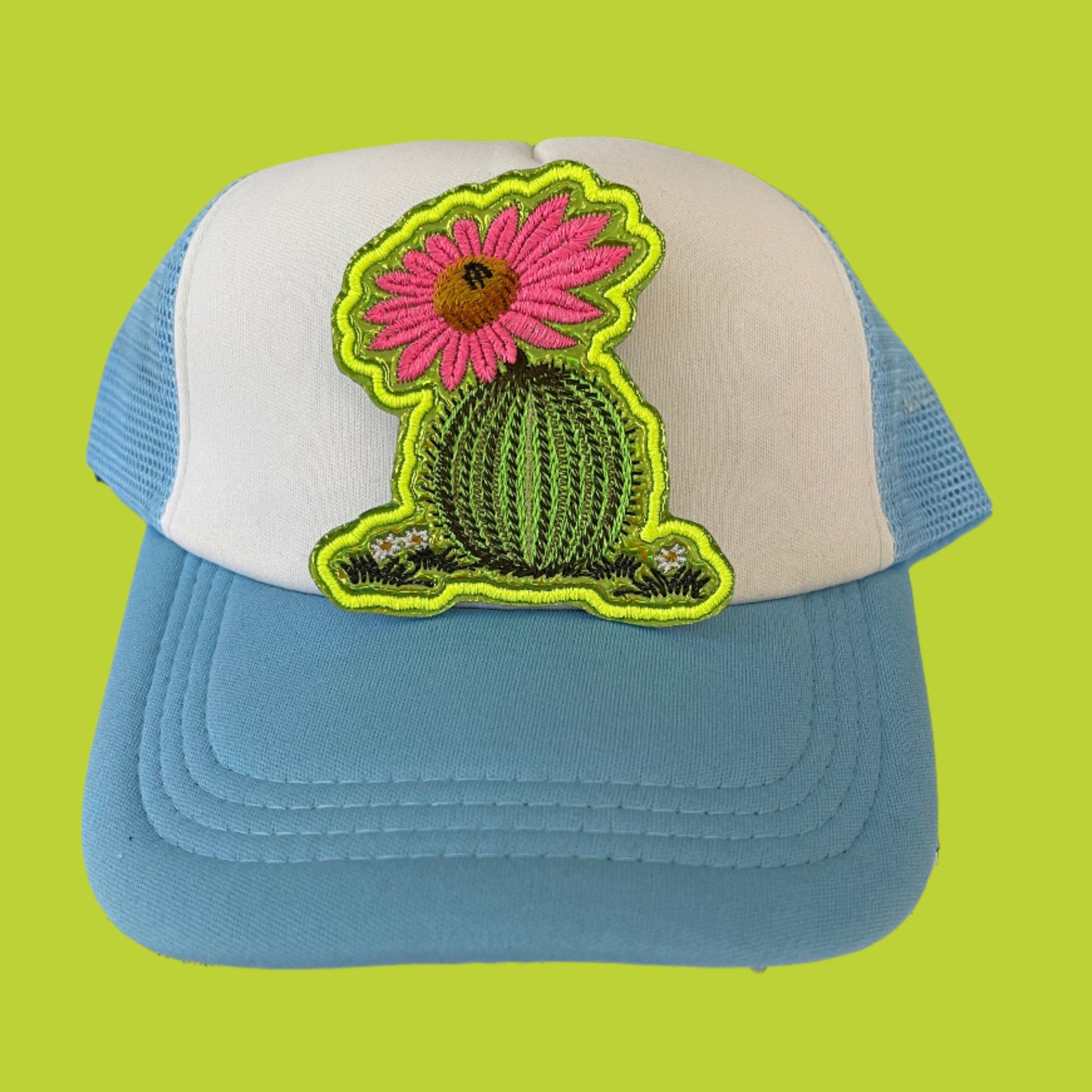 Iron-on patch featuring a green cactus with a vibrant pink flower, brown center, and neon yellow outline.