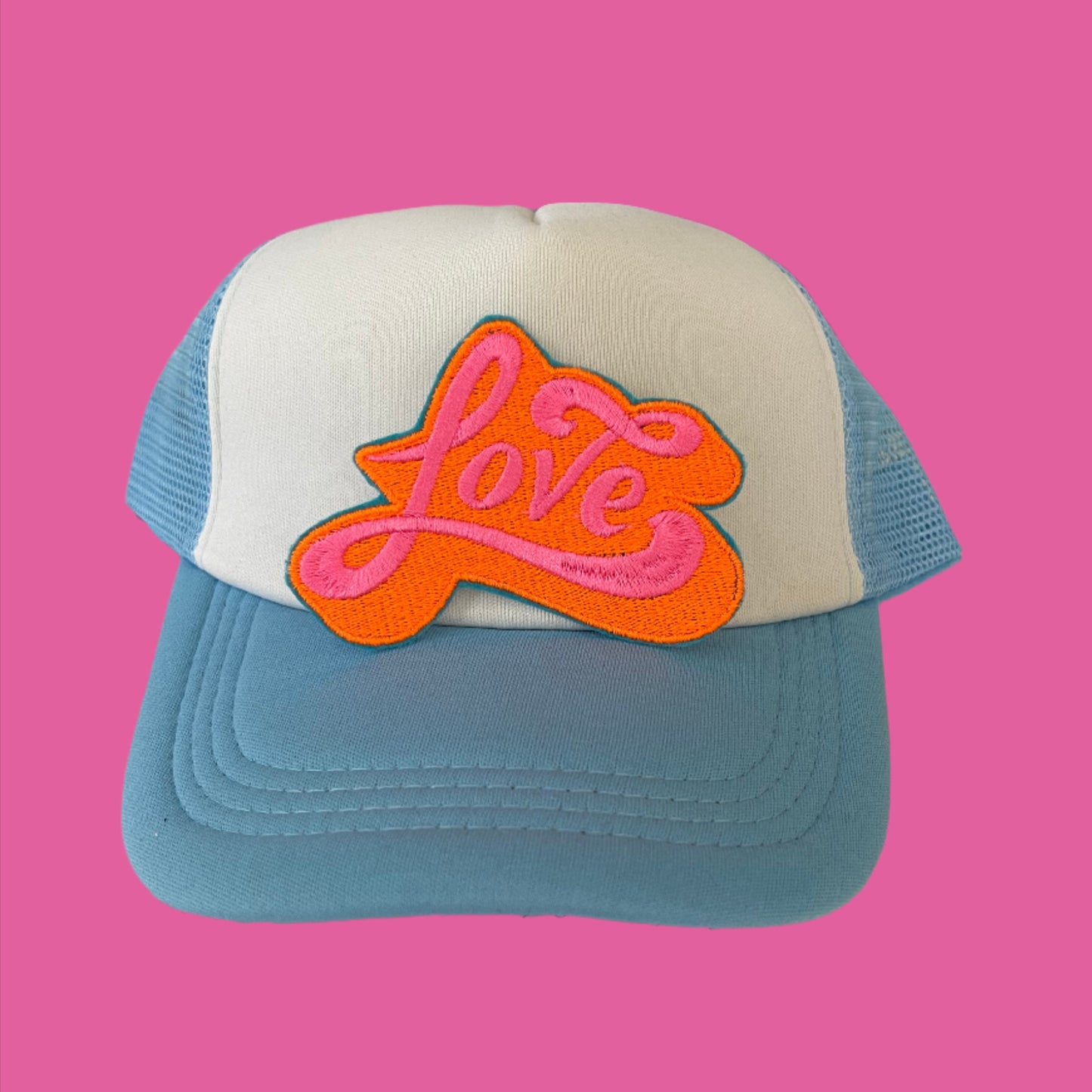 Iron-on patch featuring the word "Love" in vibrant, swirling neon pink letters against a bold orange background with an aqua outline.