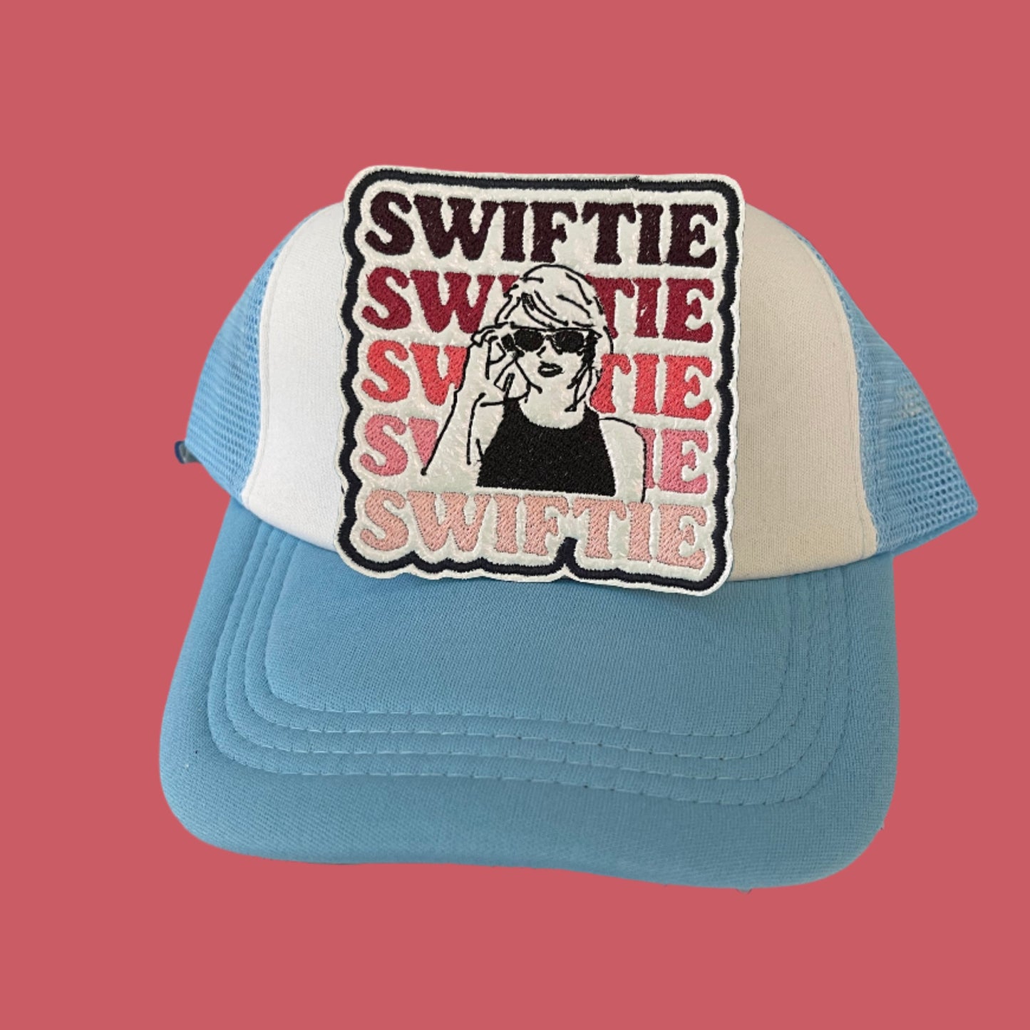 Iron-on patch featuring the word "SWIFTIE" repeated in red and pink gradient shades with a black and white illustration of a woman with sunglasses, outlined in black.