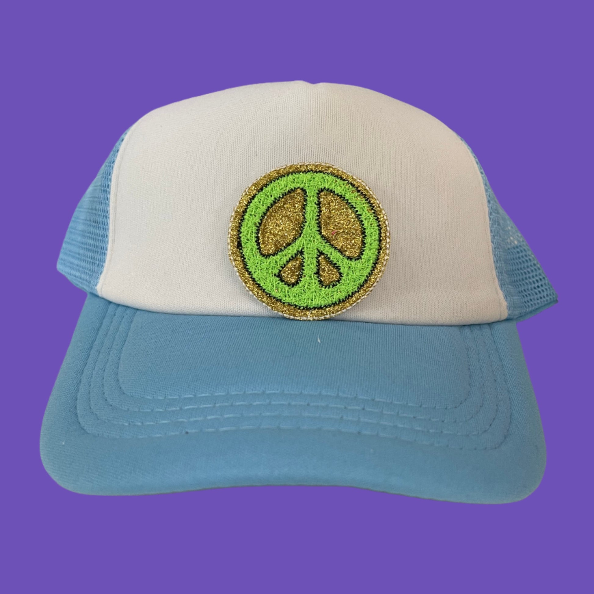 Close-up of a groovy peace sign embroidered patch with green and gold detailing, perfect for customizing hats and other accessories.