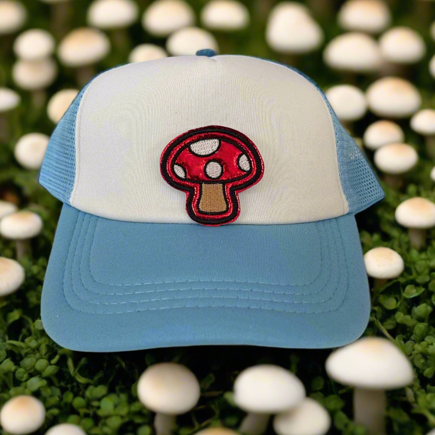 Close-up of a whimsical red mushroom embroidered patch with white spots, perfect for customizing hats and other accessories.