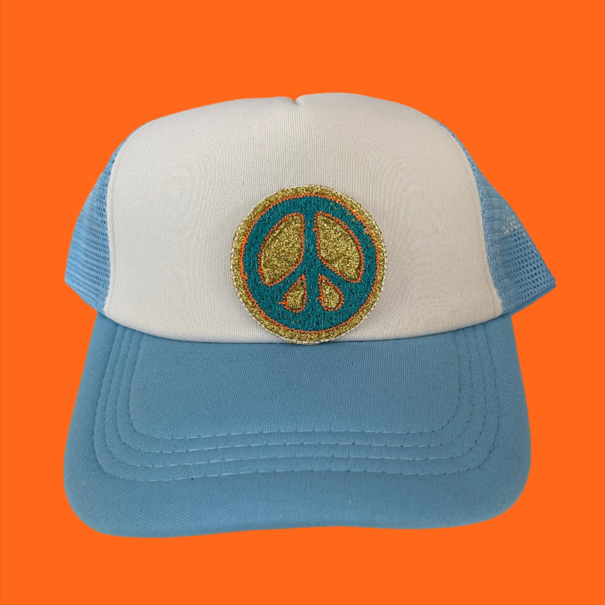 Close-up of a retro peace sign embroidered patch with blue and gold detailing, perfect for customizing hats and other accessories.