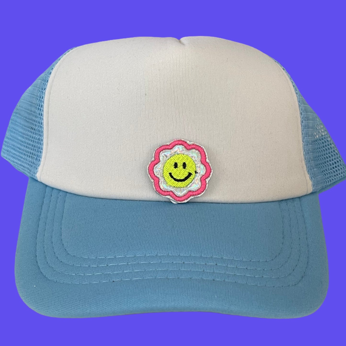 Close-up of a Smiley Flower embroidered patch featuring a bright yellow smiley face surrounded by a pink flower, perfect for customizing hats, apparel, and various accessories.