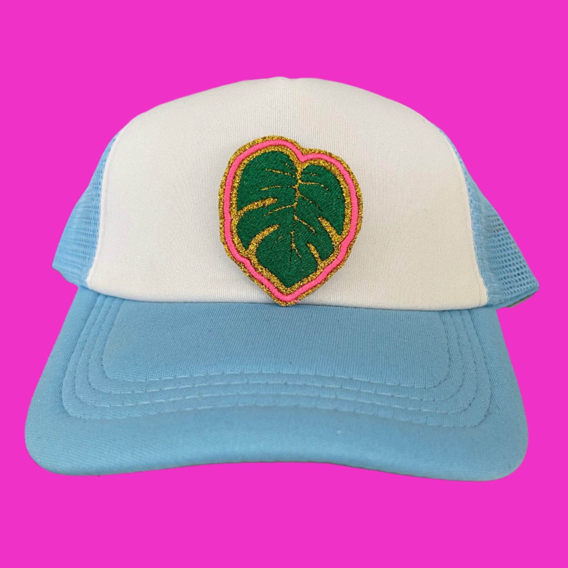 Close-up of a vibrant Monstera Leaf embroidered patch with green and pink detailing, perfect for customizing hats and other accessories.