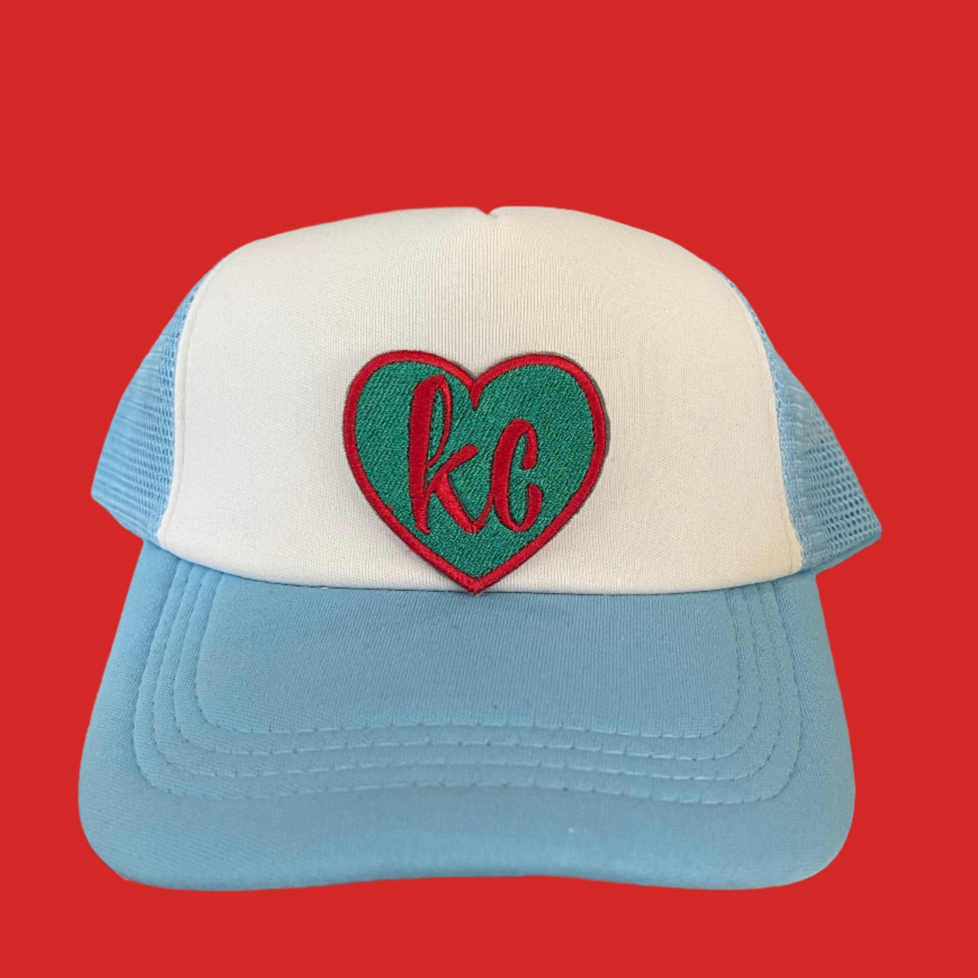 Teal heart-shaped patch with red "KC" lettering, perfect for showing Kansas City Current team pride on various accessories.