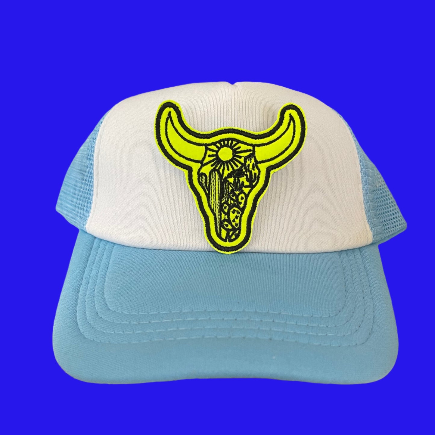 Close-up of a bright yellow bull skull embroidered patch on a hat.