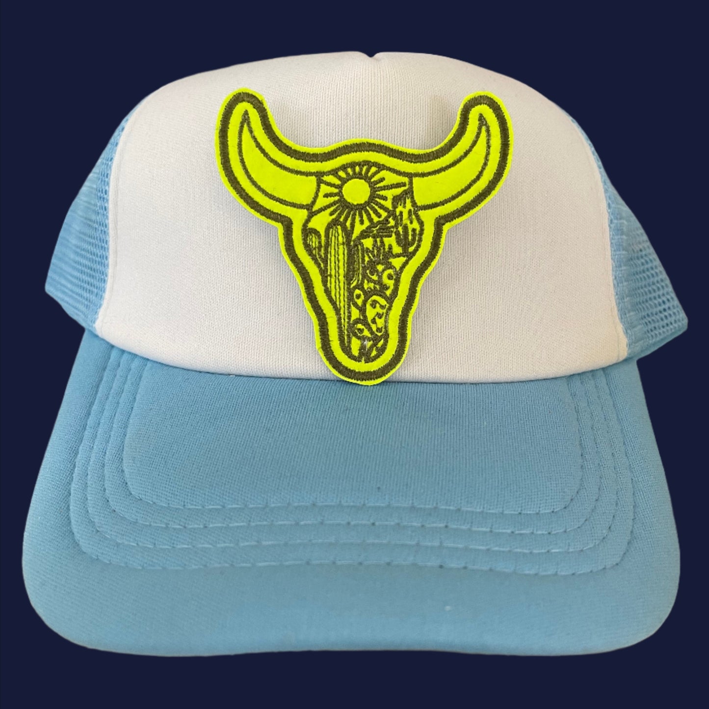 Close-up of a bright yellow bull skull embroidered patch on a hat.