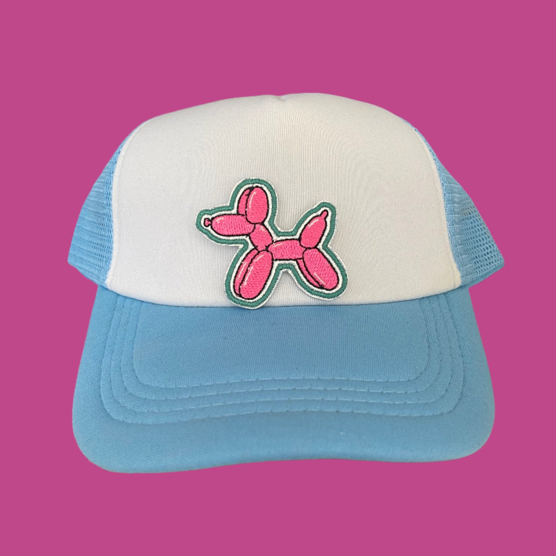 Close-up of a playful pink balloon dog patch on a hat, featuring vibrant colors and a whimsical design.