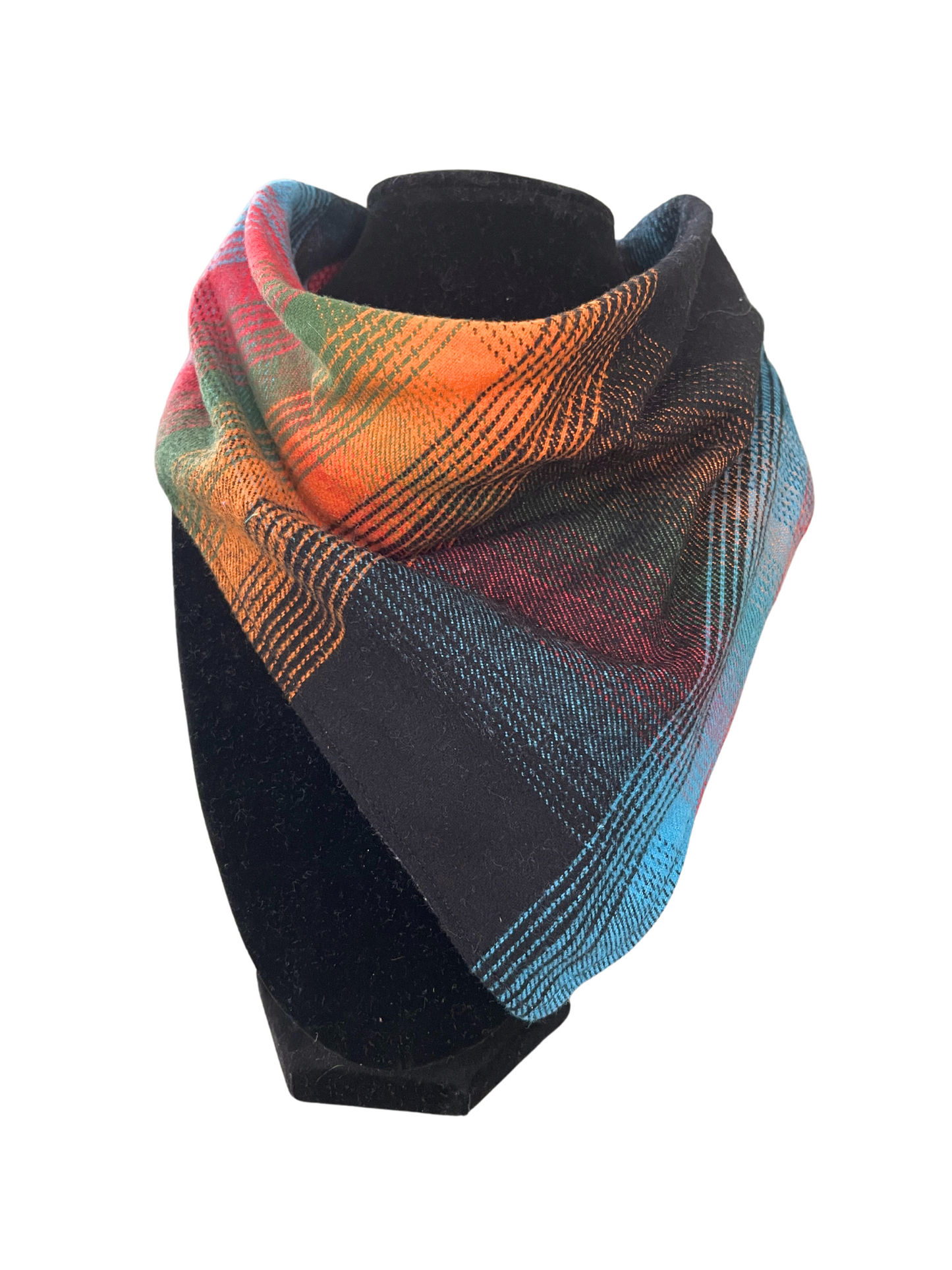 Reversible bib-dana with a rainbow plaid pattern in shades of orange, green, blue, red, and black on one side and solid color cotton flannel on the reverse, displayed on a black mannequin.