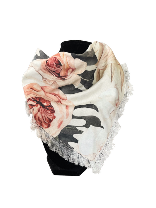 Floral print fringe bib-dana scarf with blush pink, cream, and soft green flowers on a white background, featuring adjustable snap closures, displayed on a black mannequin.