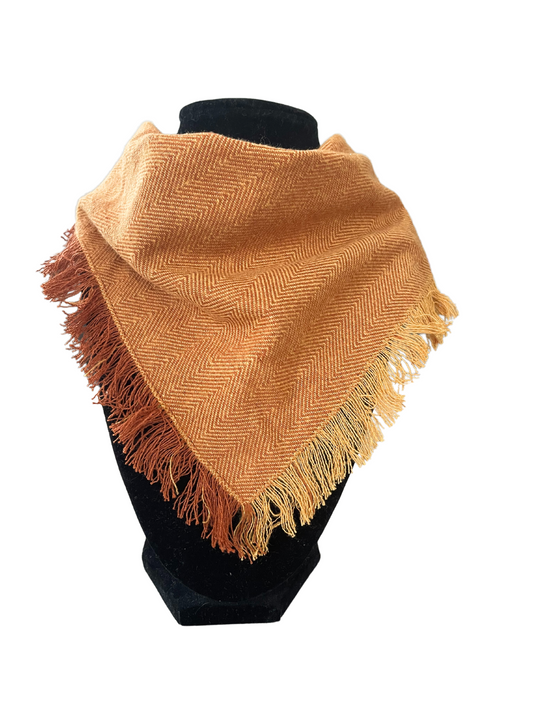 Warm orange herringbone fringe bib-dana scarf with adjustable snap closures, displayed on a black mannequin.