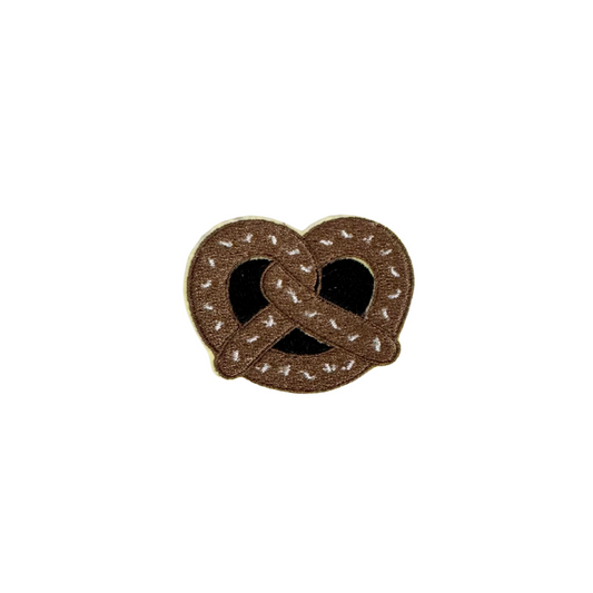 Embroidered brown pretzel patch with white salt accents.

