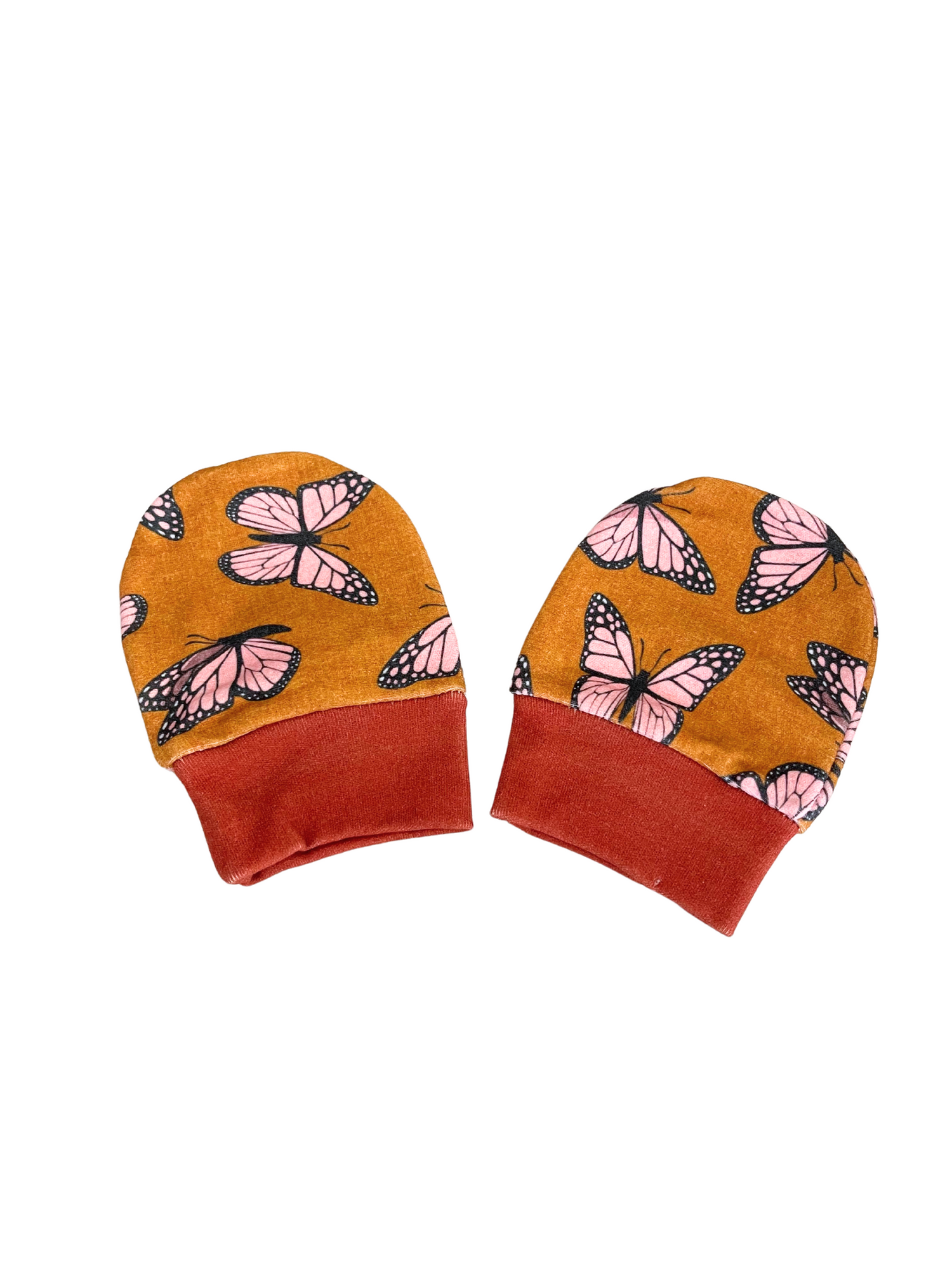 Whimsical Butterfly Baby Scratch Mittens with pink butterfly pattern and rust cuffs on mustard background.