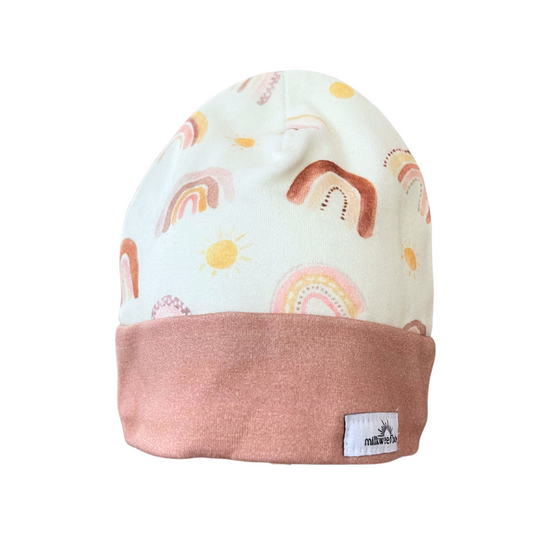 Organic cotton baby beanie with pastel rainbows and suns, rose-colored cuff, handmade in Kansas City.