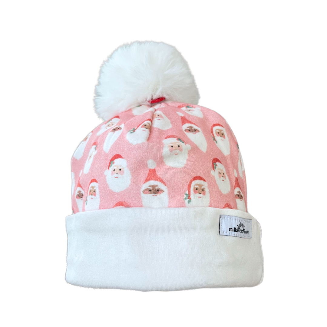 Pink baby beanie with Santa faces pattern, white fold-over brim, and faux fur pom pom.