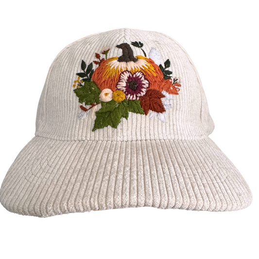 Hand-embroidered pumpkin and fall floral design on cream corduroy hat.

