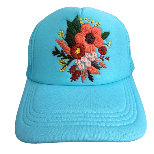 Hand-embroidered floral bouquet design on turquoise hat.

