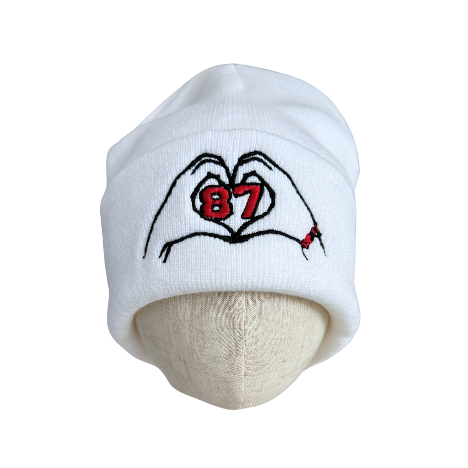 White beanie with embroidered heart hands and “87” design inspired by Travis Kelce and Taylor Swift.

