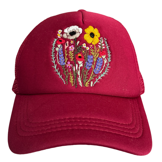 Hand-embroidered wildflower design on a red trucker hat with a detailed floral pattern.
