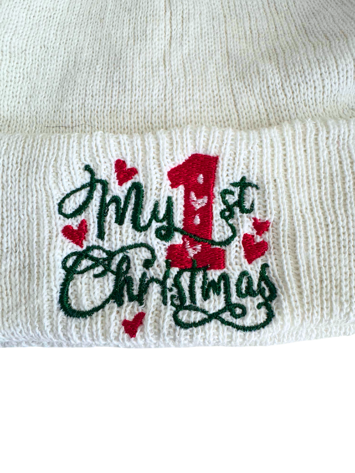 White baby beanie with "My 1st Christmas" embroidered in red and green, featuring red hearts.

