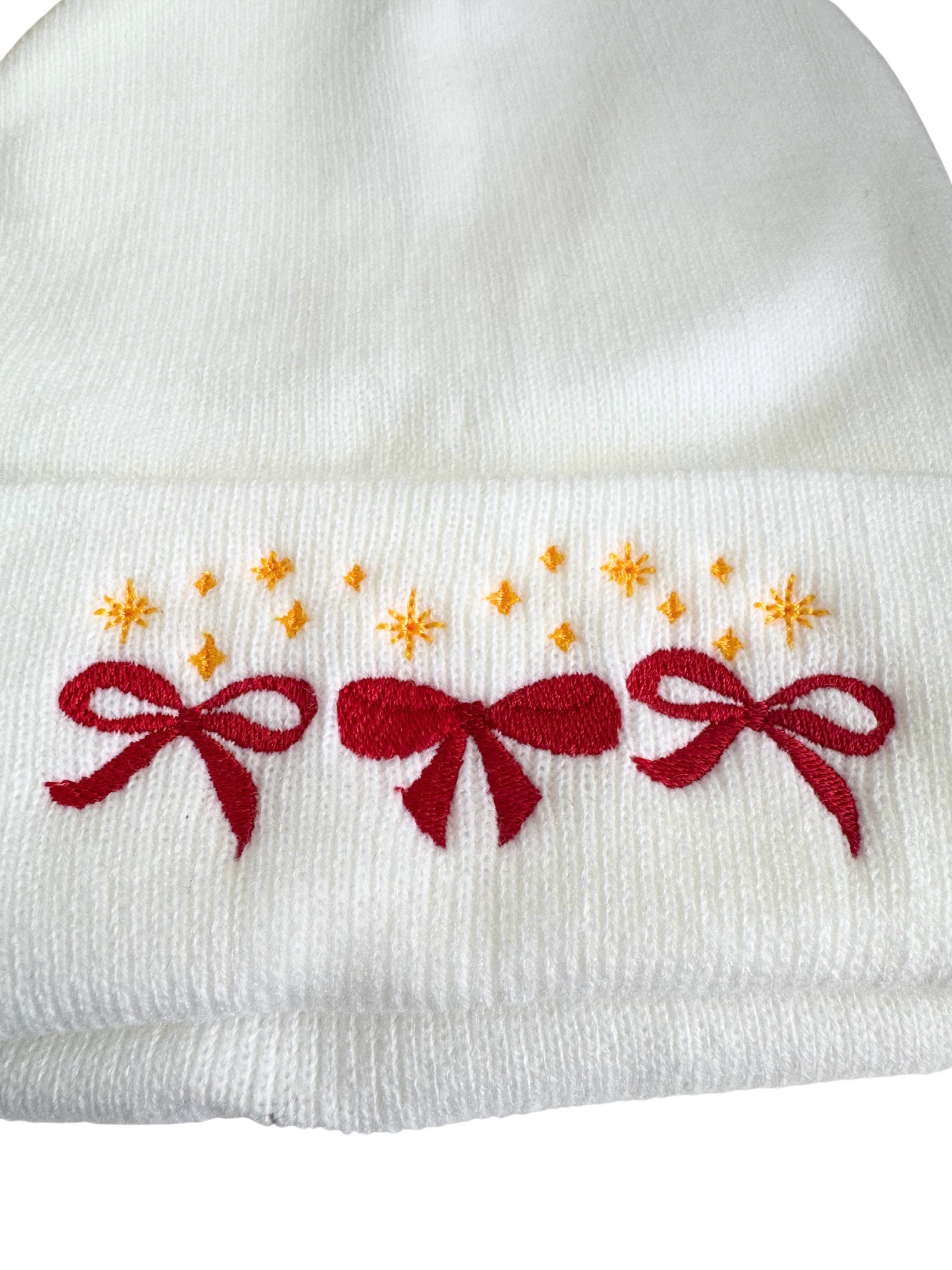 White beanie with red bows and golden star embroidery in Kansas City Chiefs colors.

