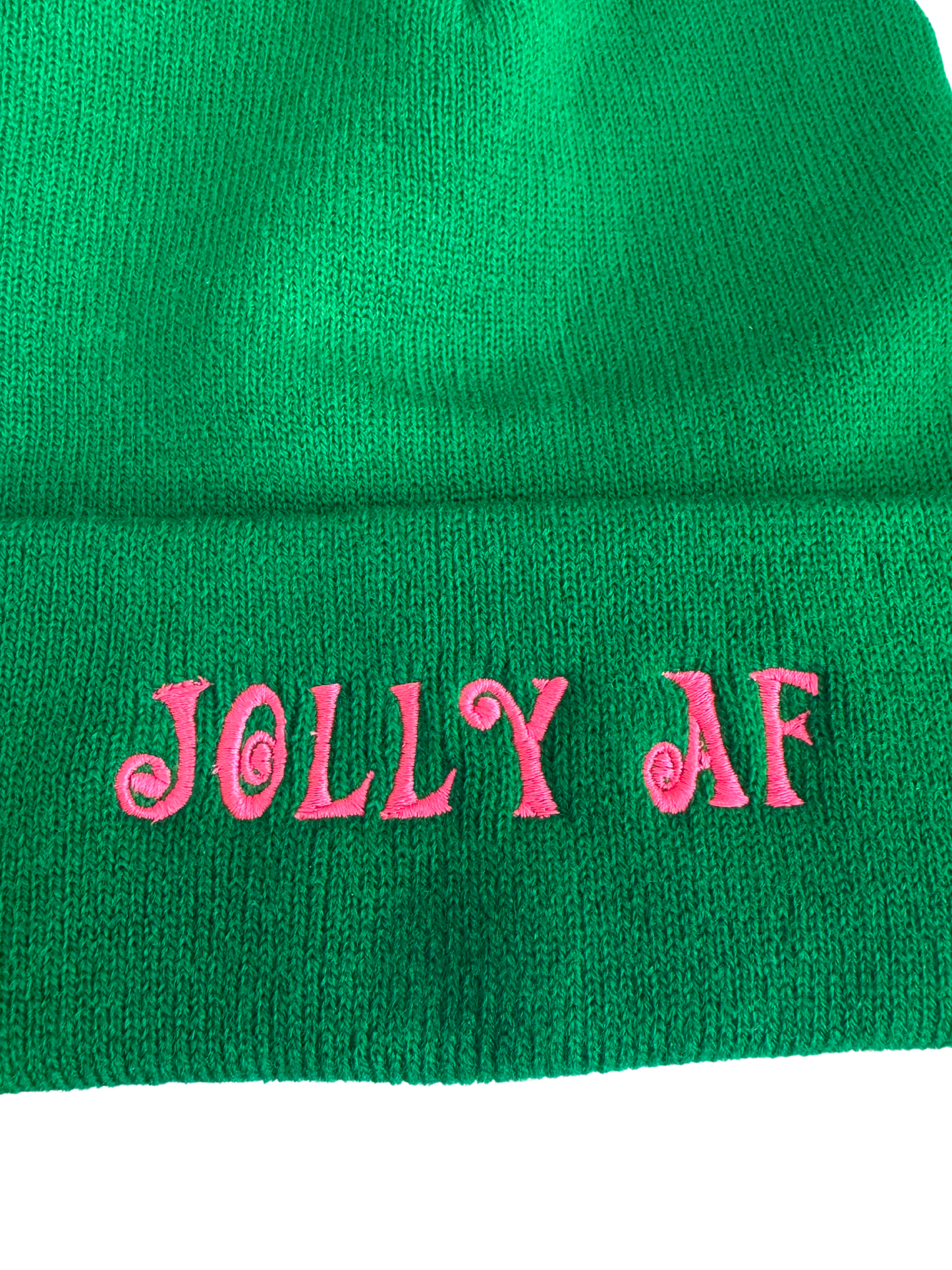 Green beanie with pink "Jolly AF" embroidery in swirled lettering, displayed on a mannequin head.

