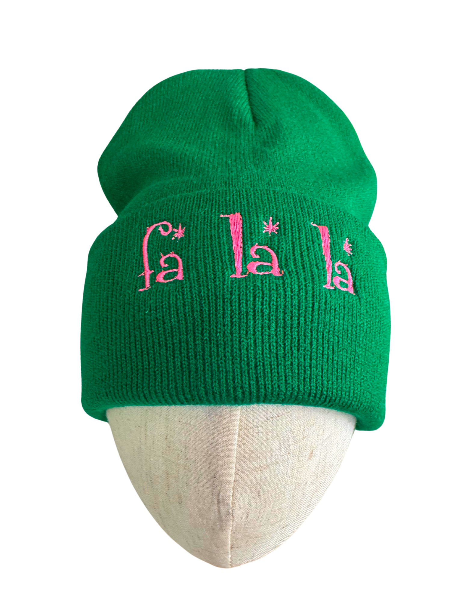 Green beanie with pink "Fa La La" embroidered text, festive winter holiday theme.

