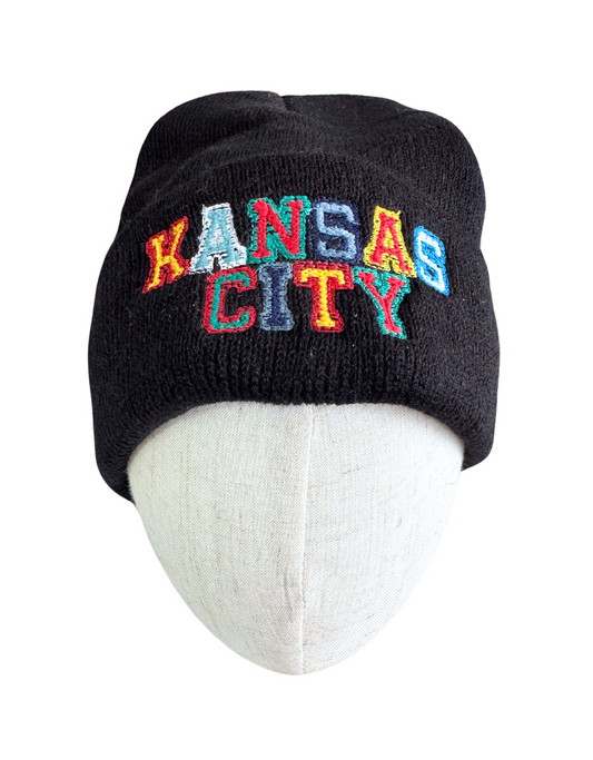 Black knit beanie with "Kansas City" embroidered in multicolored lettering representing KC sports teams.

