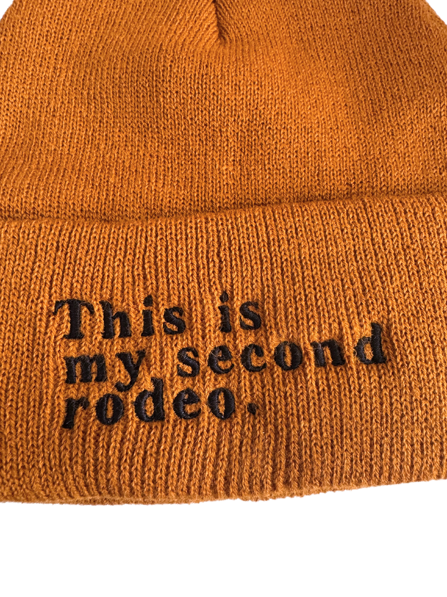 Dark orange beanie with "This is my second rodeo" embroidered in black thread

