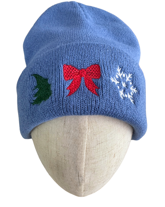 Blue holiday beanie with machine-embroidered Christmas tree, red bow, and snowflake designs.

