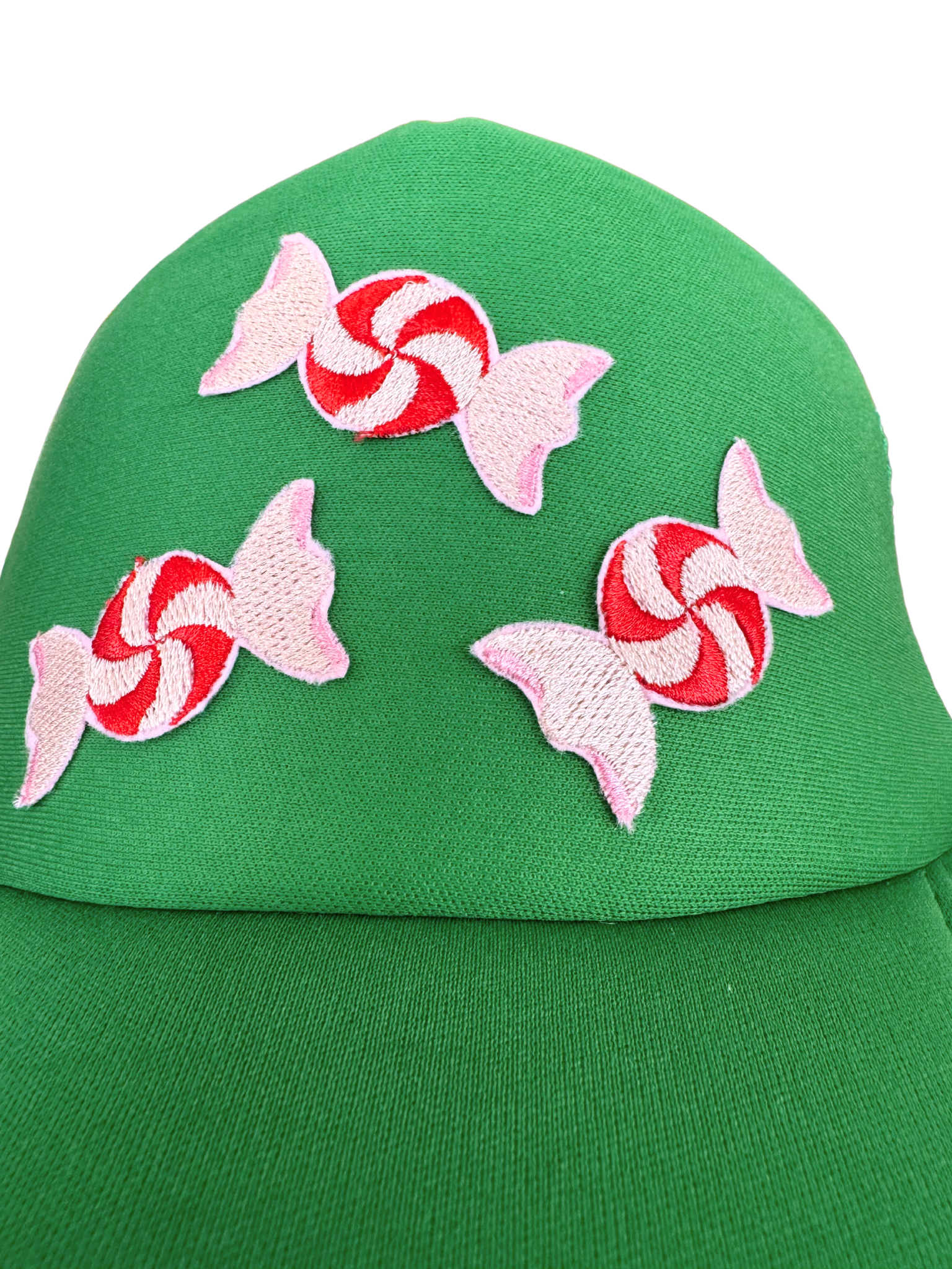 Green trucker hat with embroidered red and white peppermint candy designs.

