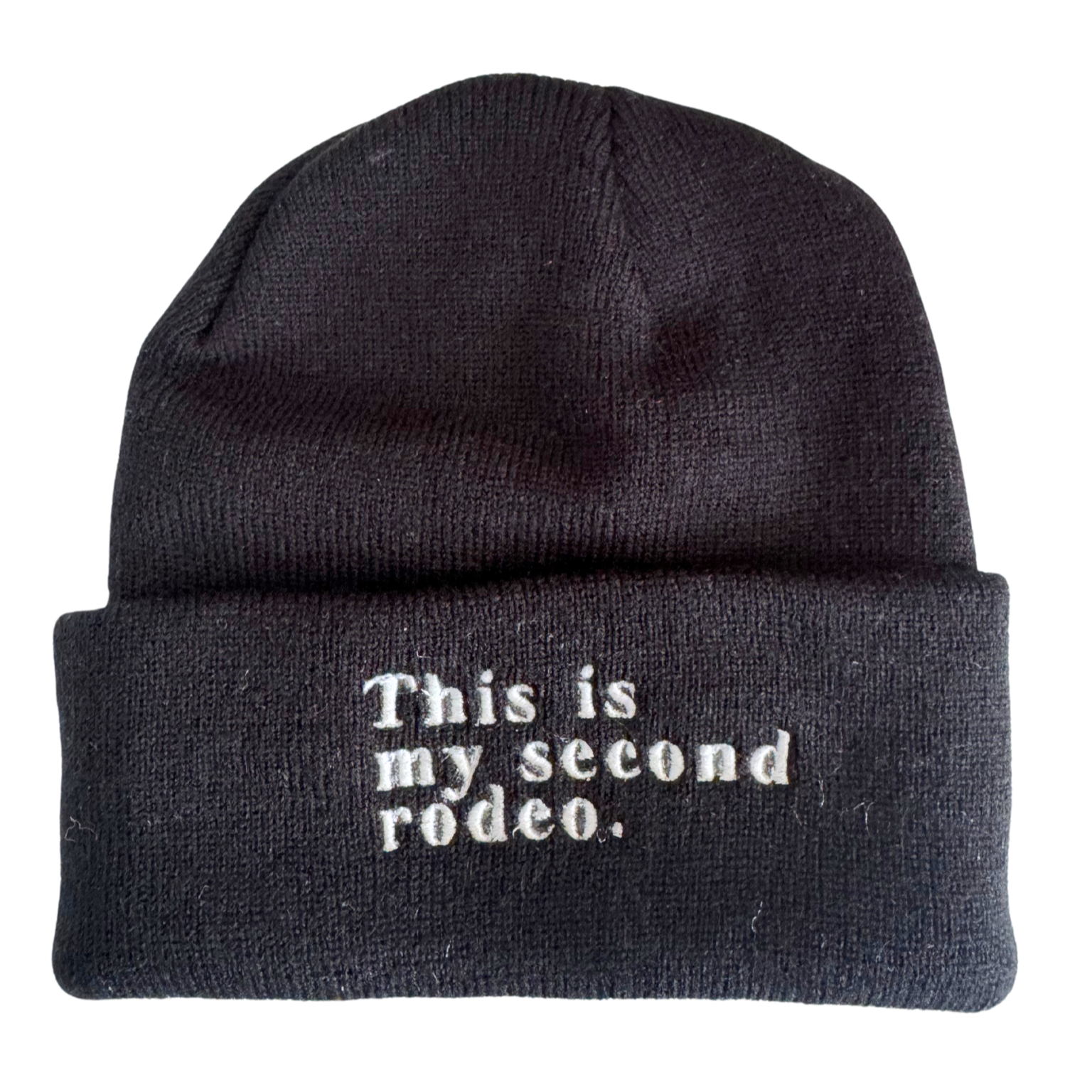 Black beanie with white embroidered text saying "This is my second rodeo."

