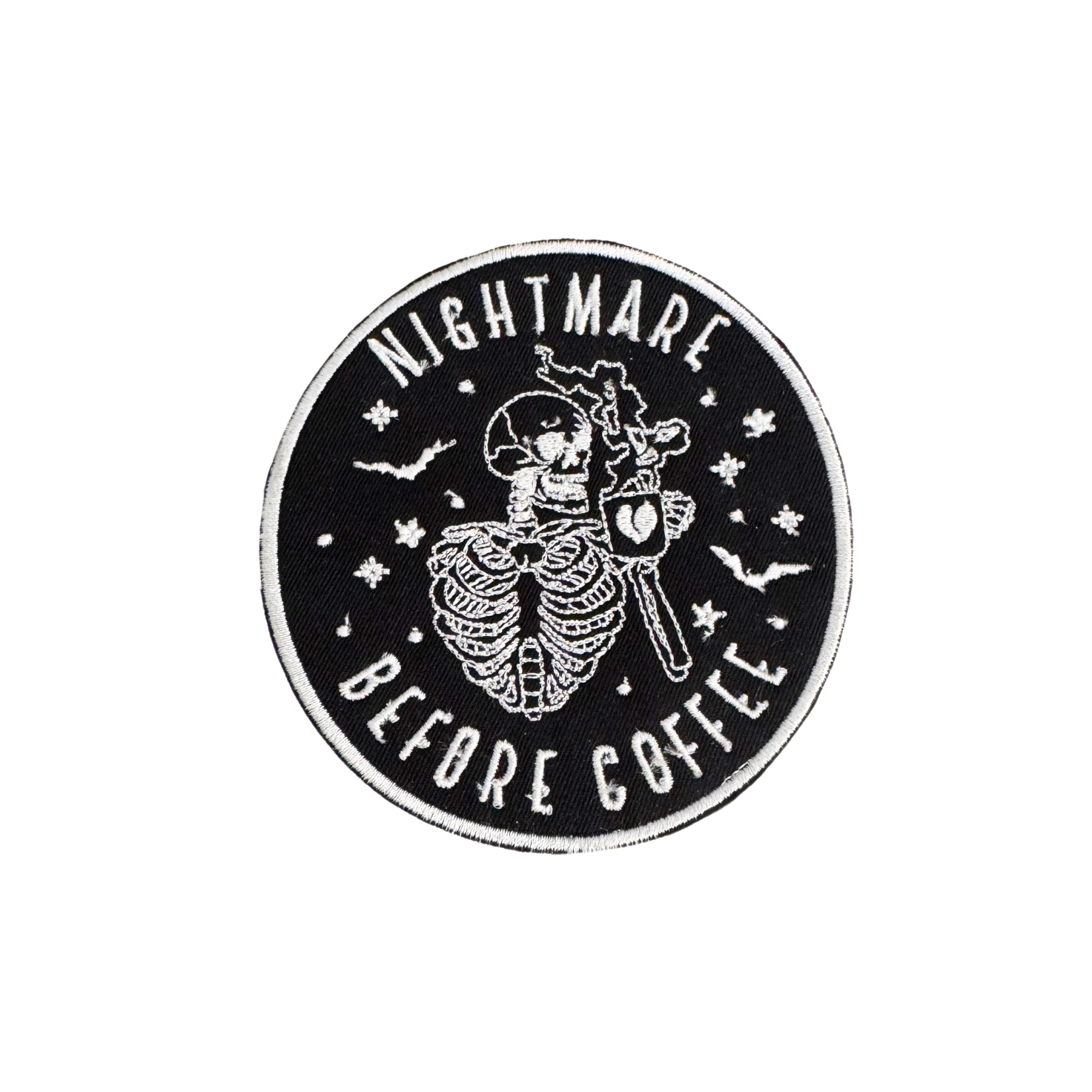 "Nightmare Before Coffee" skeleton iron-on patch with bats and stars on black background.