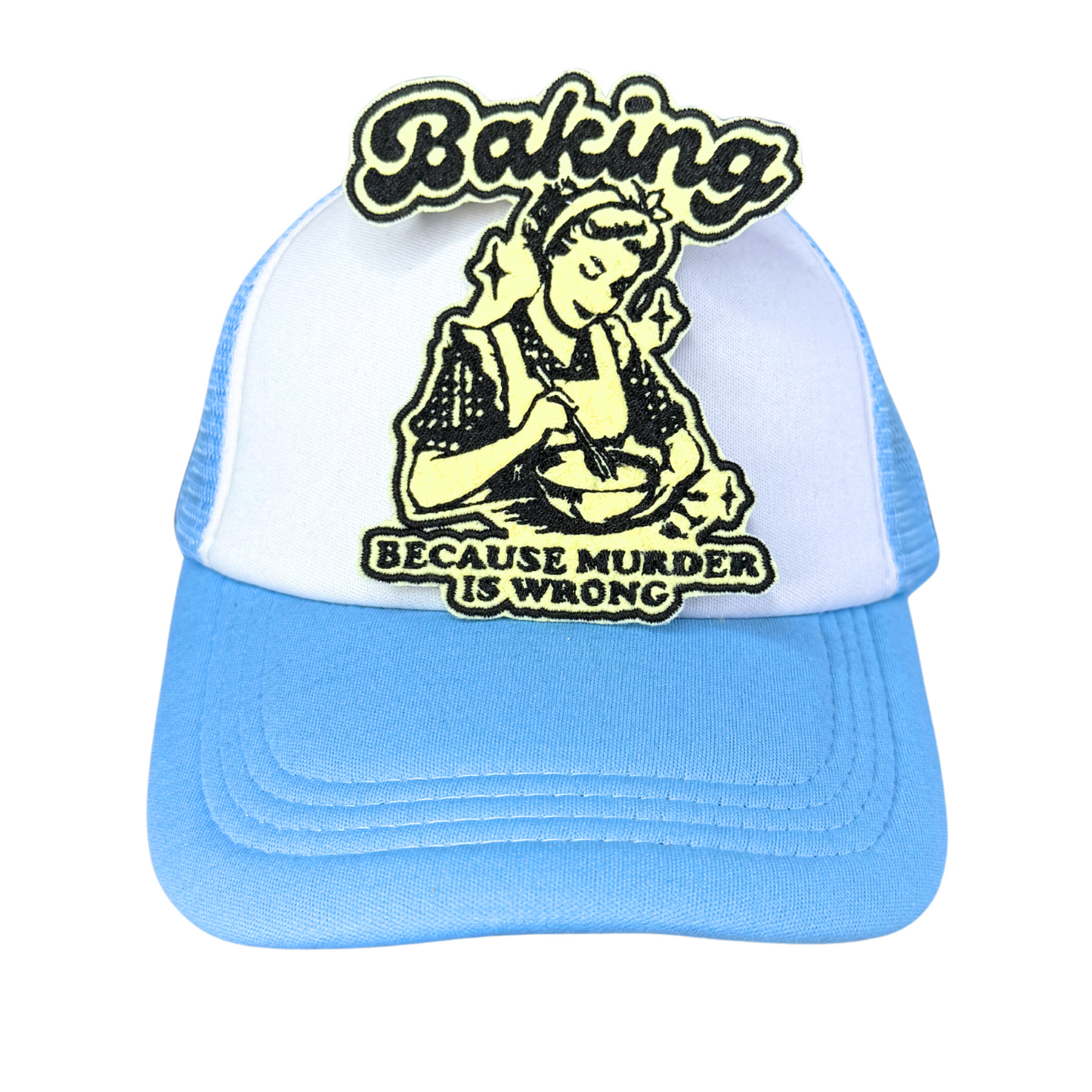 "Blue and white trucker hat with an embroidered 'Baking Because Murder is Wrong' patch in black and cream colors."
