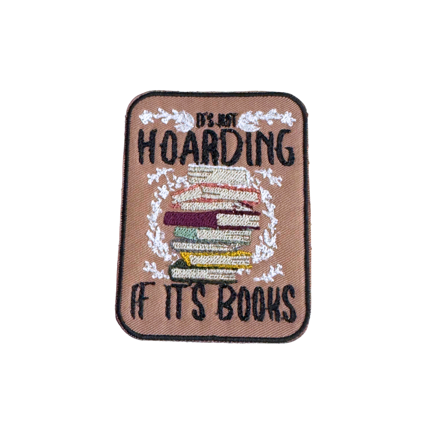 Embroidered patch with a stack of books and the phrase "It's Not Hoarding If It's Books" on a neutral background with floral details.
