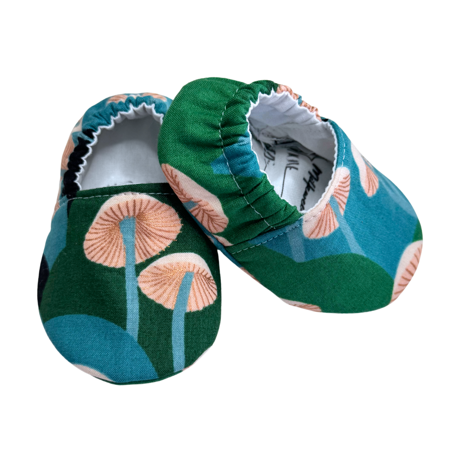 Side view of handmade mushroom-print baby moccasins, showcasing the flexible soft soles and elastic back for a secure, stay-on fit.

