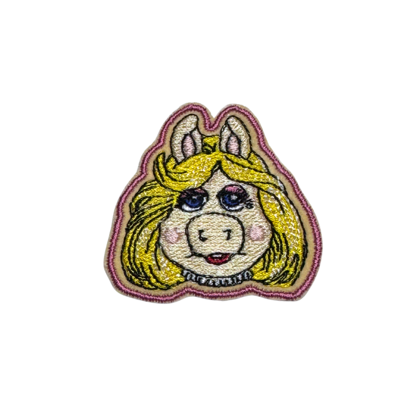 Embroidered patch featuring a glamorous blonde pig with blue eyes and a confident expression.
