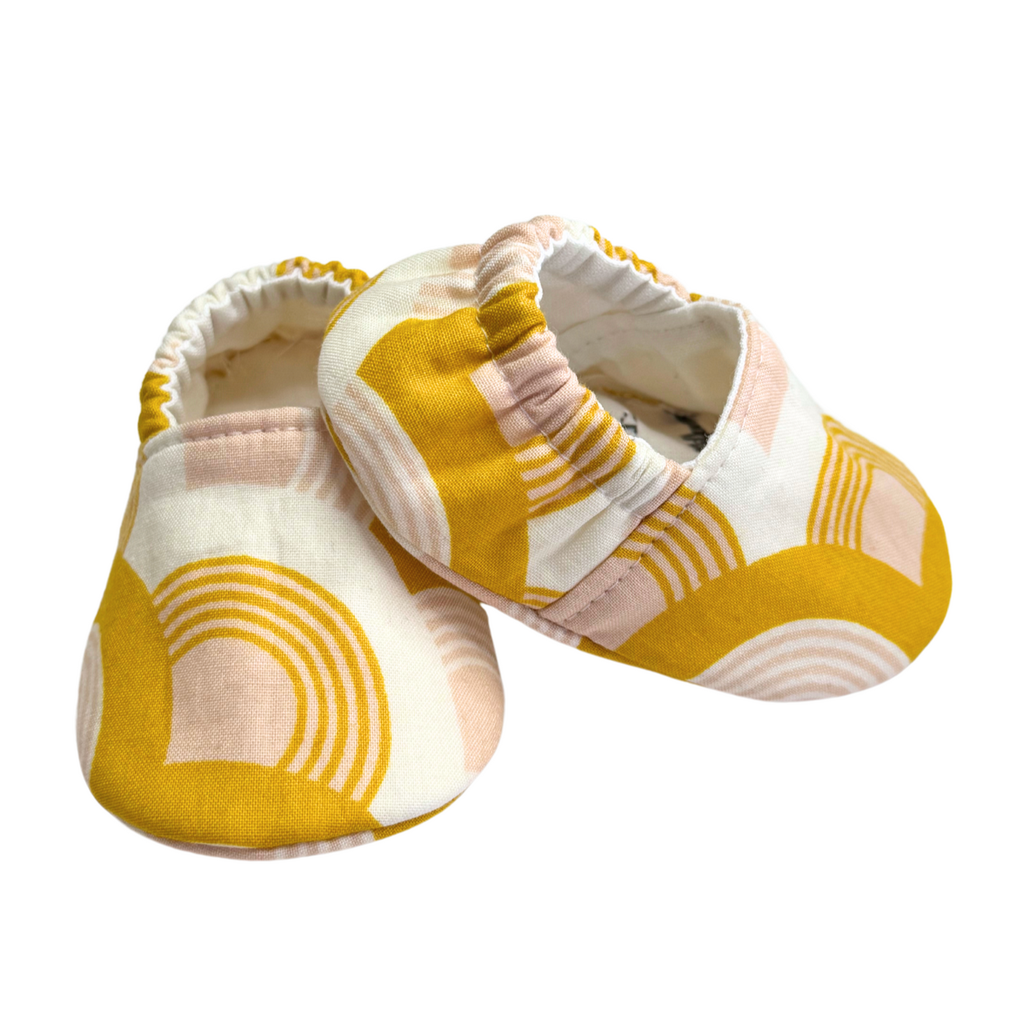 Side view of handmade golden rainbow baby moccasins, showing flexible soft soles and a snug, stay-on elastic back.

