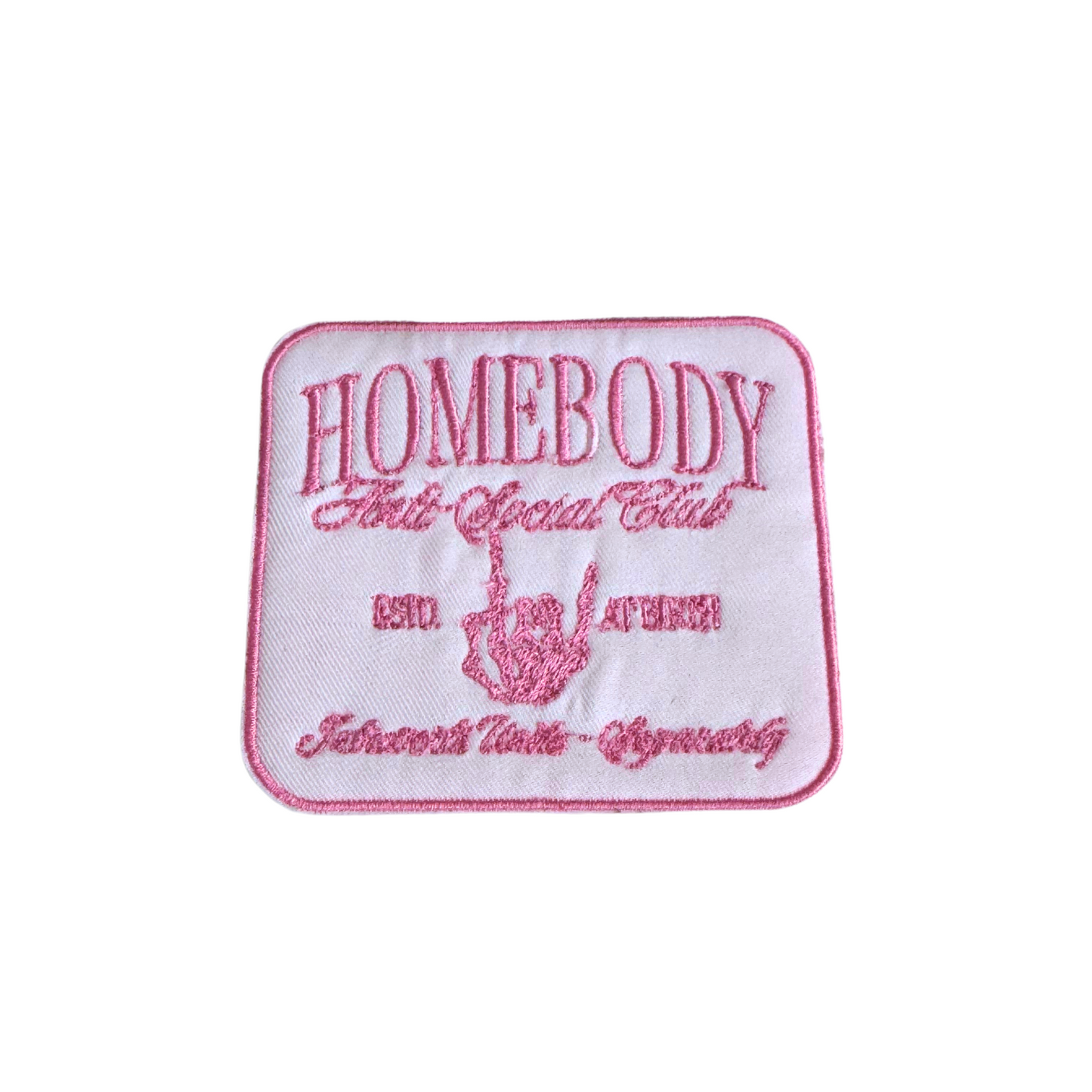 Close-up of embroidered Homebody Anti-Social Club patch in pink and white.
