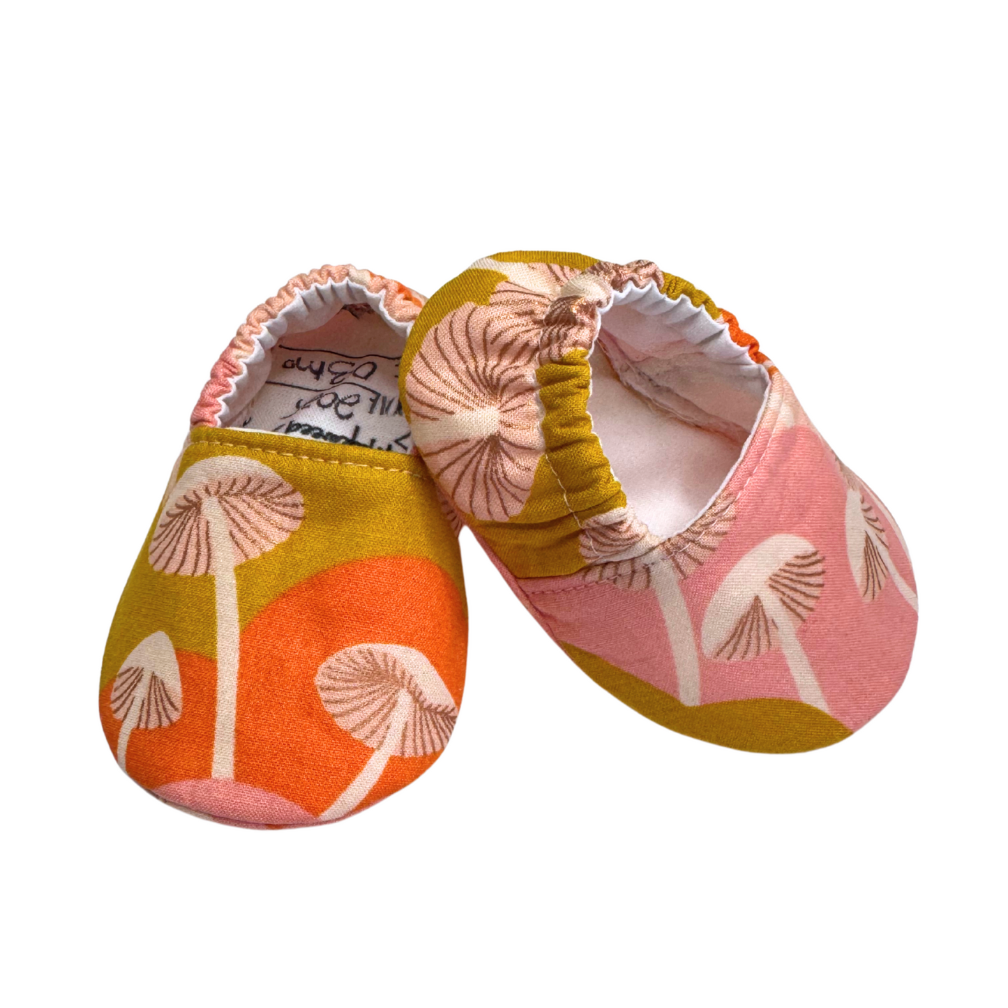 Side view of handmade mushroom-print baby moccasins, showing flexible soft soles and vegan materials, designed for early foot development.