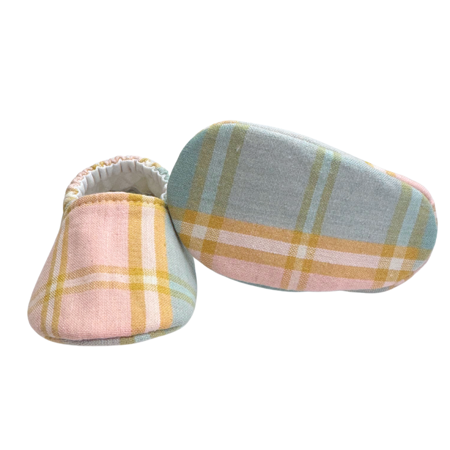 Bottom view of pastel plaid baby moccasins, highlighting the soft, flexible sole designed for newborn foot development and all-day comfort.

