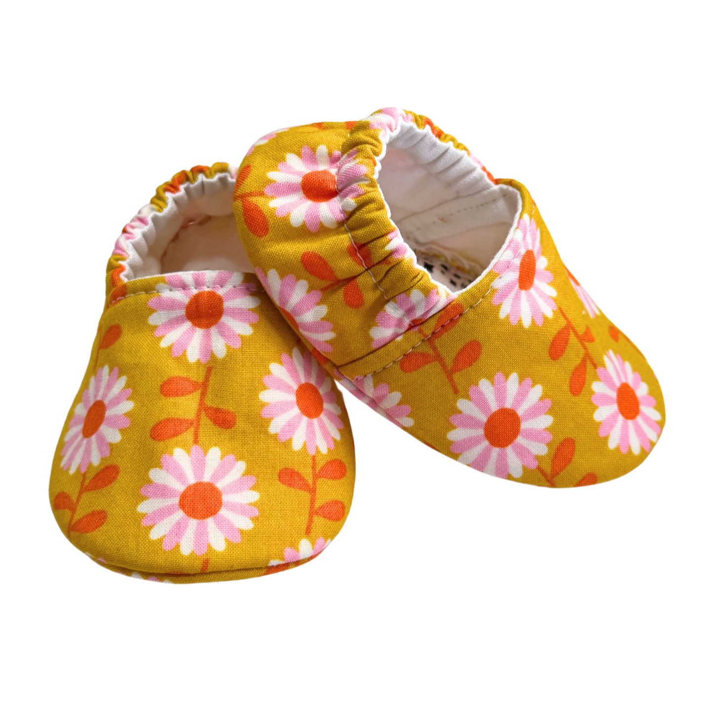 Side view of handmade daisy baby moccasins, showing soft soles, lightweight vegan fabric, and a stay-on elasticized back.