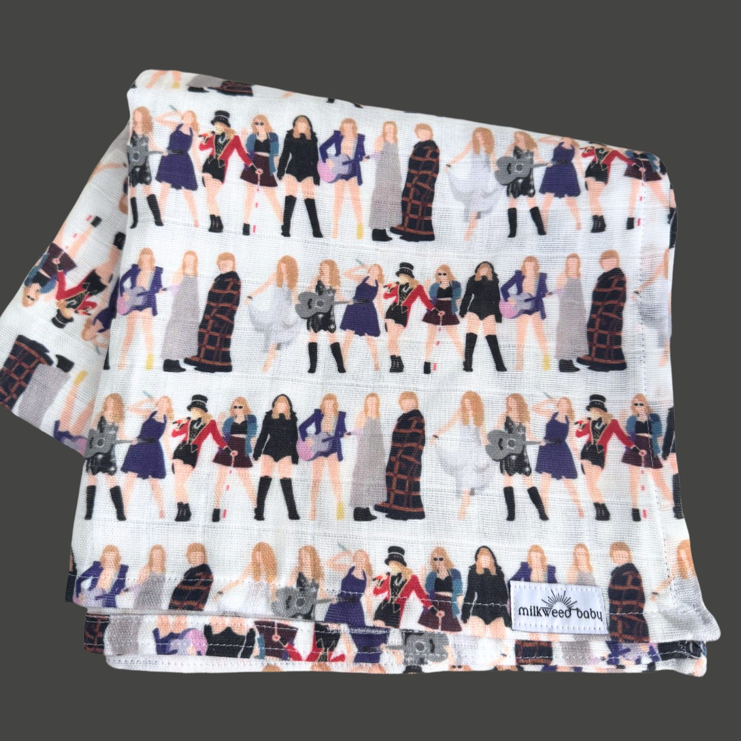 Taylor Swift-inspired baby swaddle blanket displayed on a dark background, featuring a repeating design of tour outfits from different eras. Made of soft, organic Sweet Pea Gauze.

